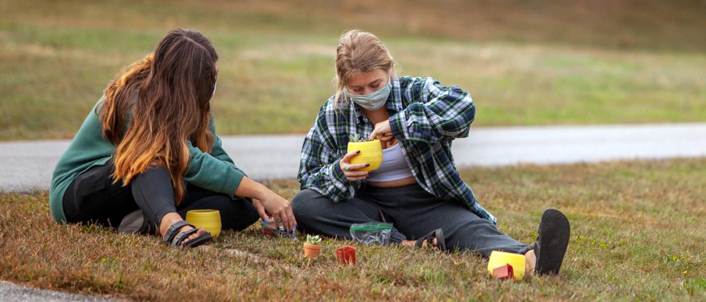 Two students planting succulents outside on the Biddeford Campus